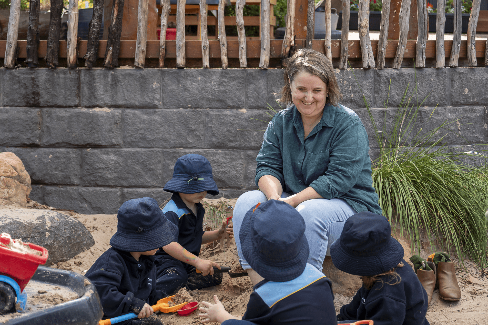Principal Evie Stevens is with some early learning centre students. The students are playing in the sandpit.
