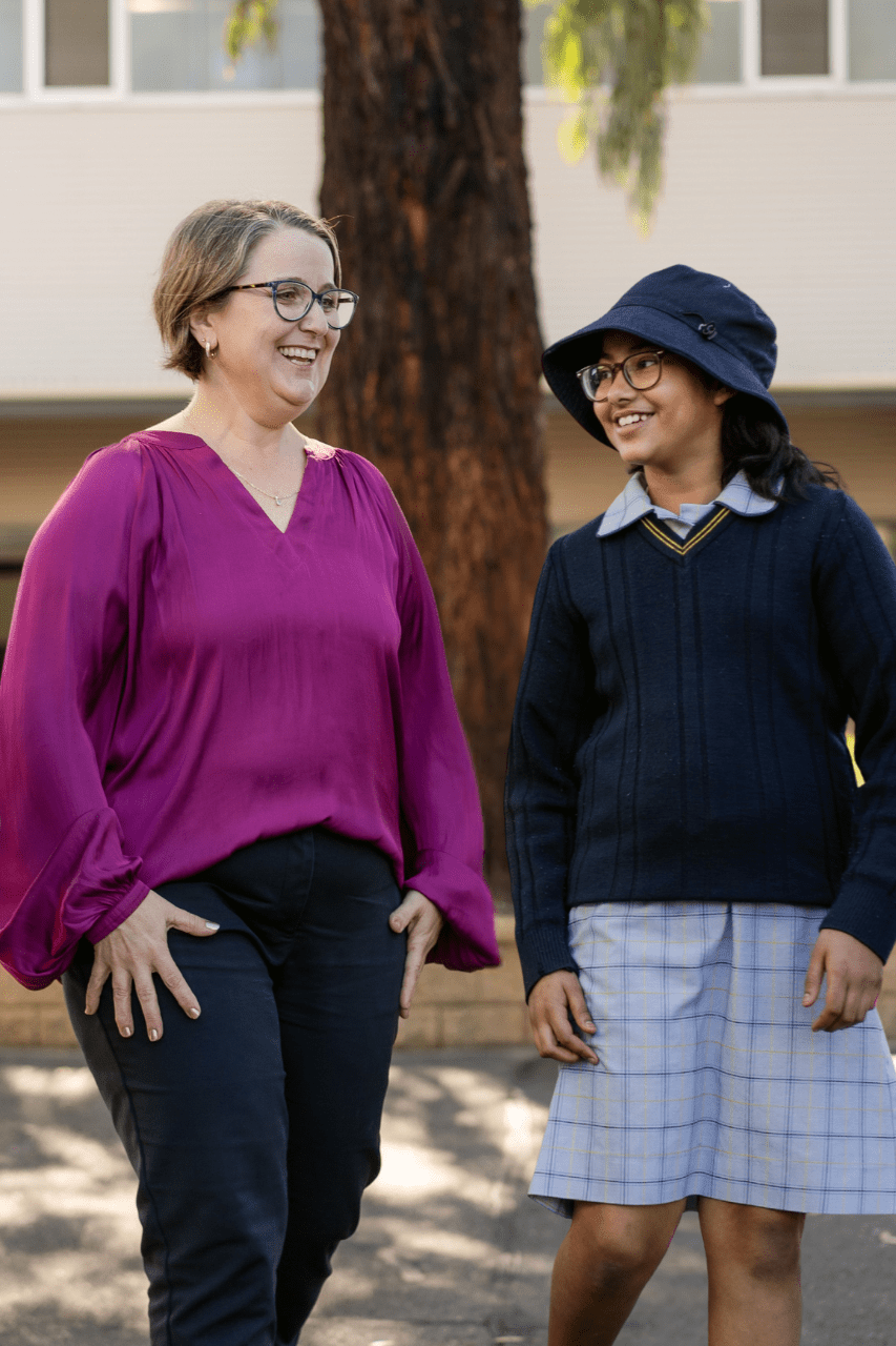 Principal Evie Stevens and a student of Good Shepherd Lutheran School are walking together outside while on a school tour. They are both smiling.