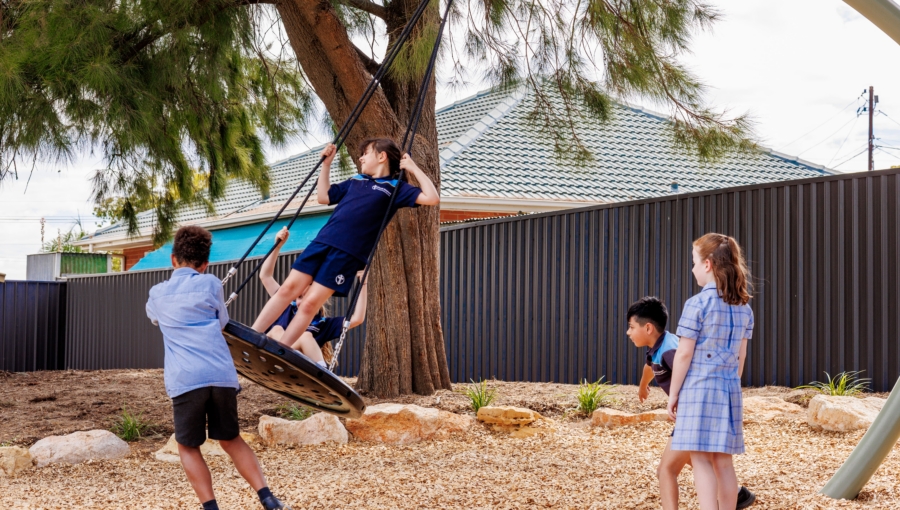 Students of Good Shepherd Lutheran School are playing on a large pendulum swing.
