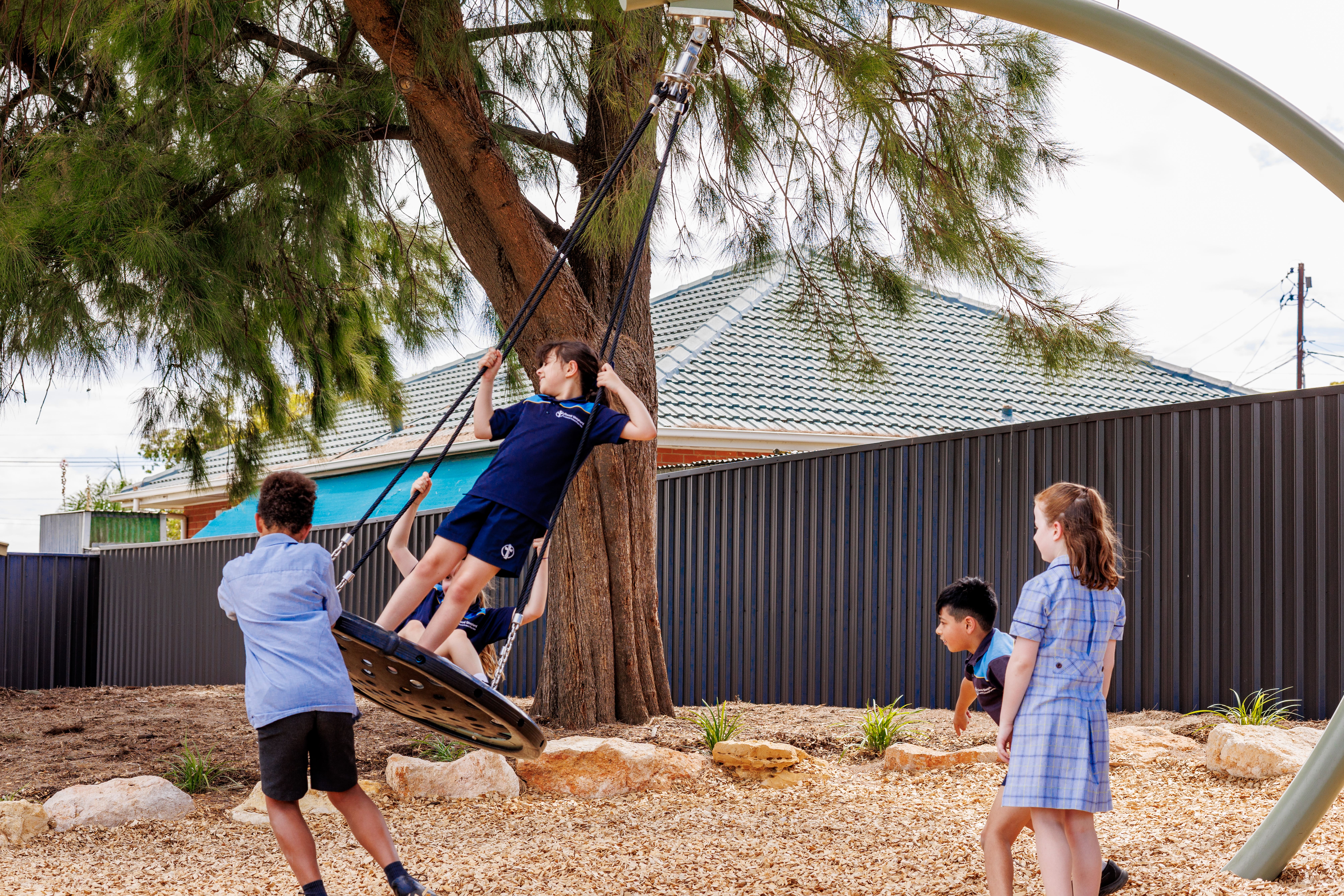 Students of Good Shepherd Lutheran School are playing on a large pendulum swing.
