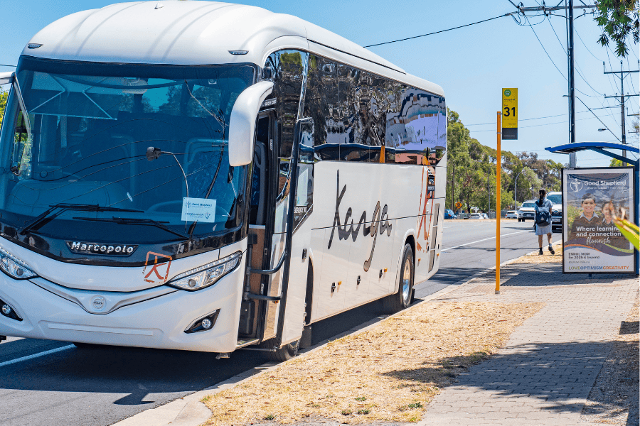 A school bus is waiting by a bus stop.