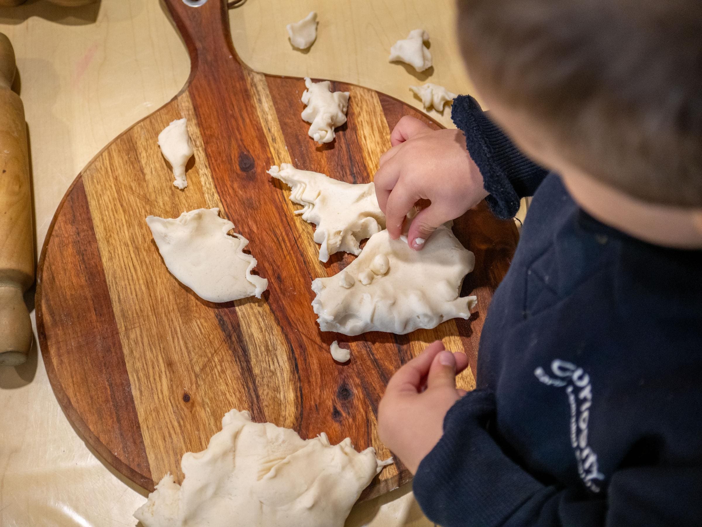 A photo over the shoulder of a Curiosity ELC student learning with playdough.